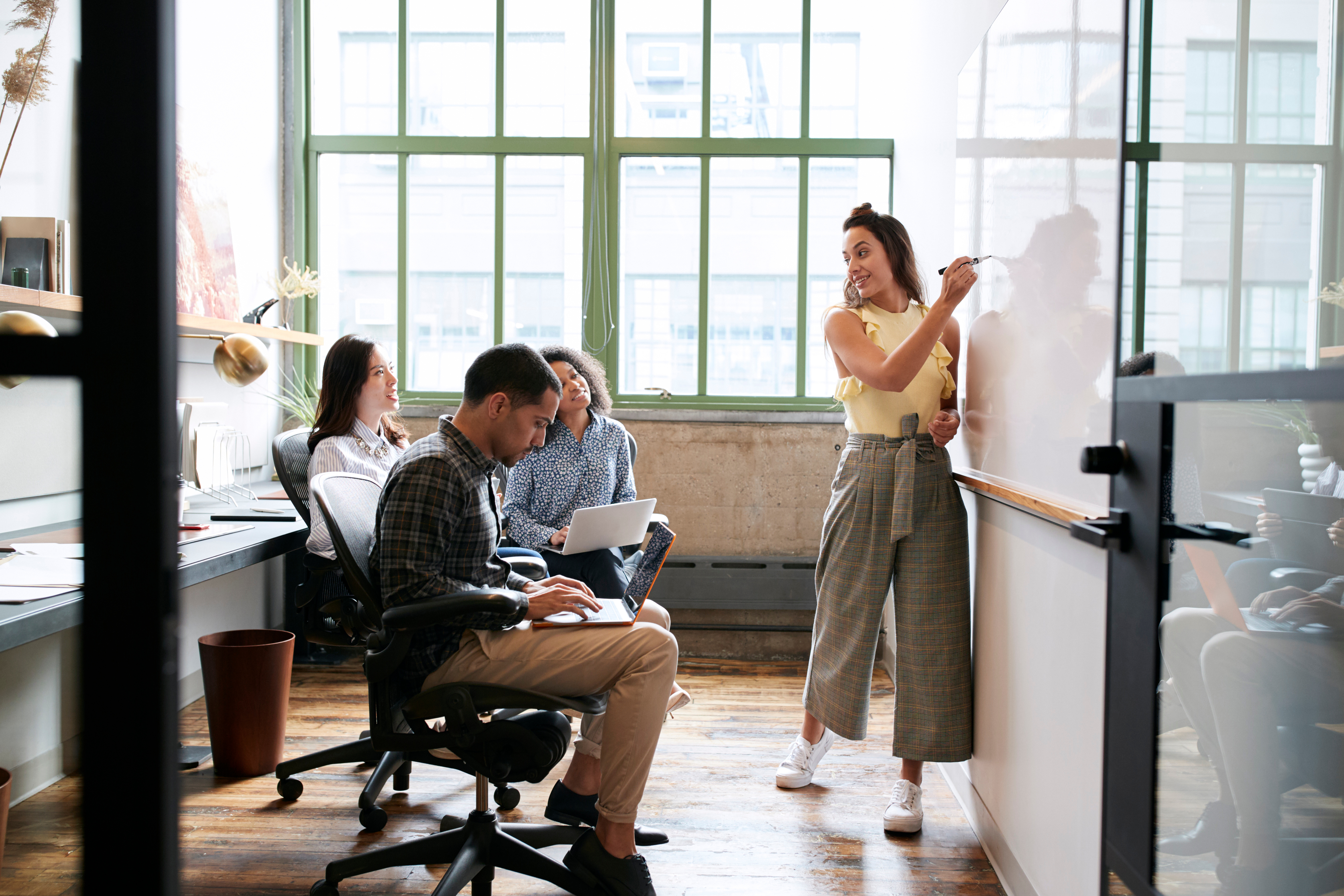 woman leading brainstorm session with whiteboard and coworkers