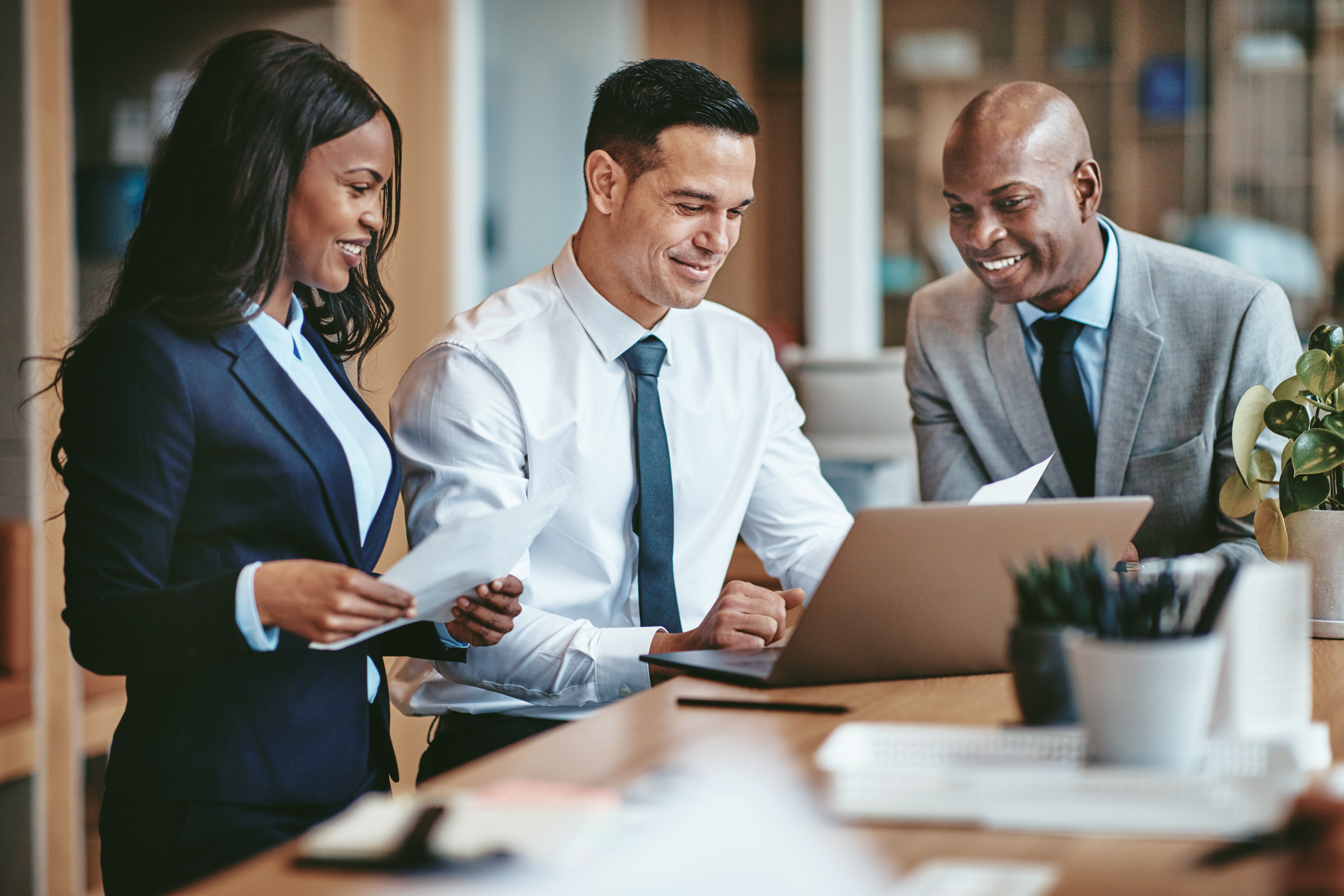 three businesspeople looking at papers and laptop